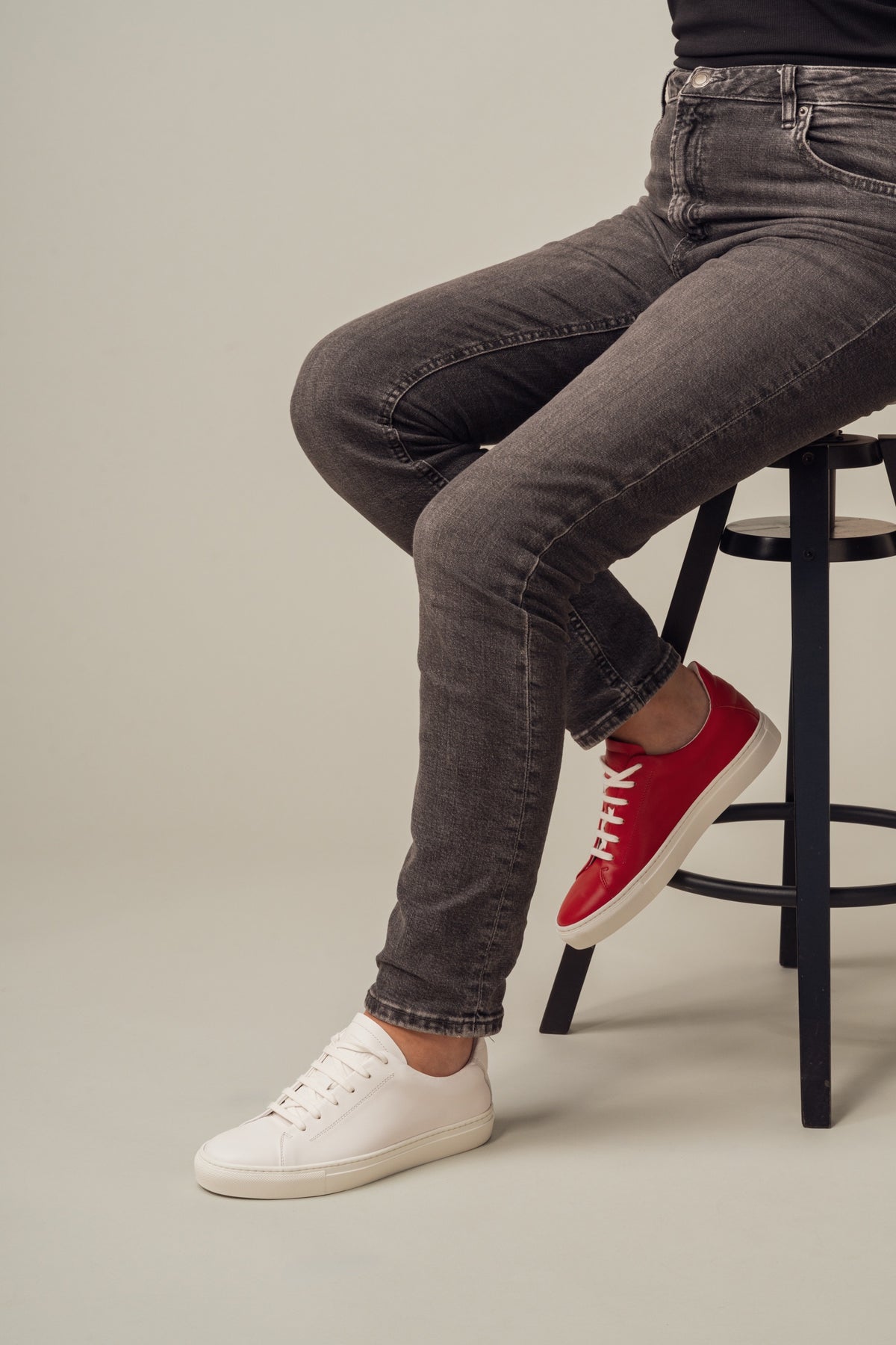A seated woman in jeans wearing one red and one white sneaker